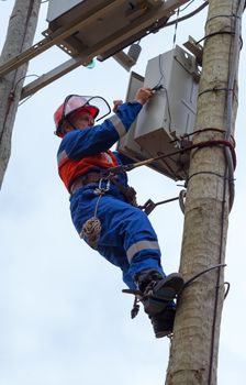 Electrician perform maintenance on the transmission towers recloser  with the use of claws- manholes and  belt