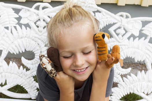 A young girl looking content with eyes closed playing a game with finger puppies