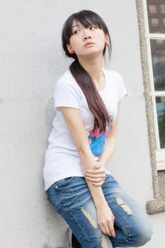 Asian girl leaning against limestone wall