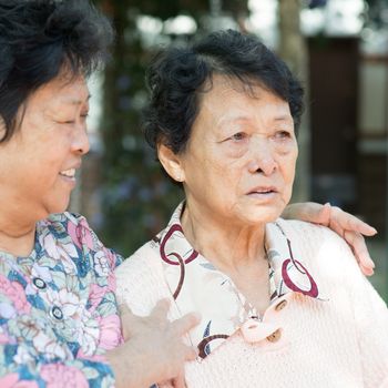 Asian mature woman consoling her crying old mother at outdoor natural green park. 