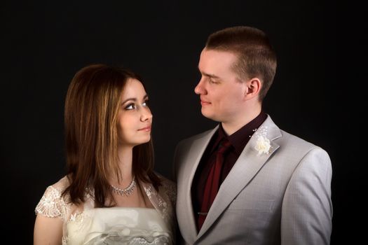 the bride and groom on a black background in the studio looking at each other
