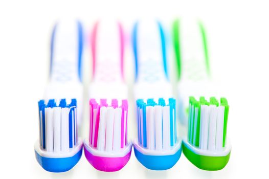 four new multi-colored toothbrushes are on a white background