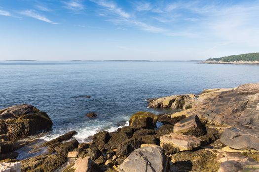 This image shows the contrast between a peaceful sea and a rugged, rocky shore at Acadia National Park.