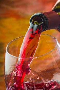 Wine pours into the glass of the bottle on a colored background