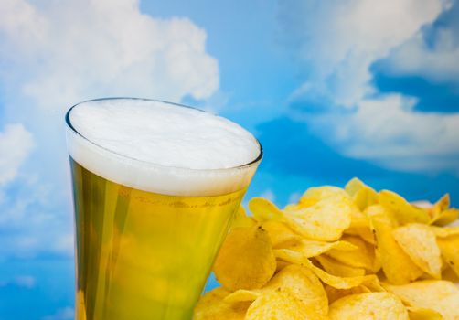 foamy beer in a glass with potato chips