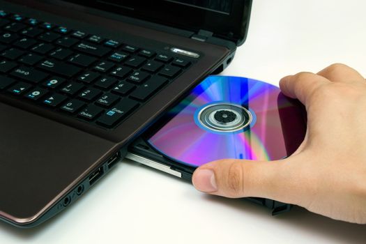 Man insert compact disc from laptop