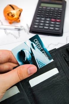 Personal credit card in wallet. Piggybank and calculator in background