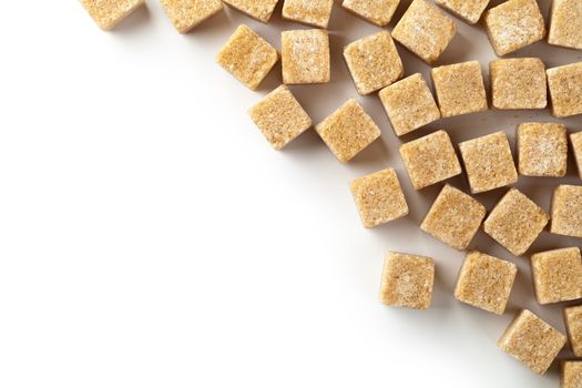 Brown cane sugar cubes on white background with copy space. Top view