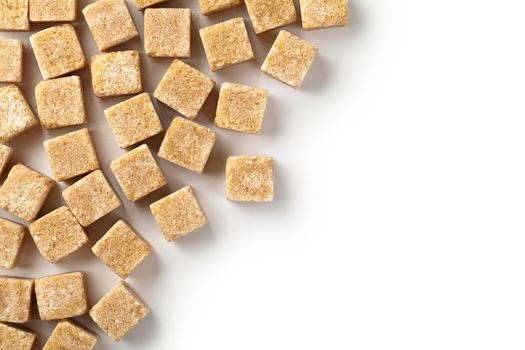 Brown cane sugar cubes on white background. Copy space. Top view