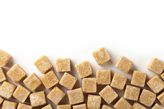 Brown sugar cubes on white background with copy space. Top view