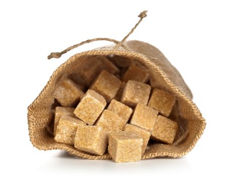 Brown sugar cubes in sack on white background. Macro shot