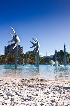 Deserted section of the beach and Fish Sculptures at the Esplanade swimming lagoon in Cairns with bathers visible in the distance in the water