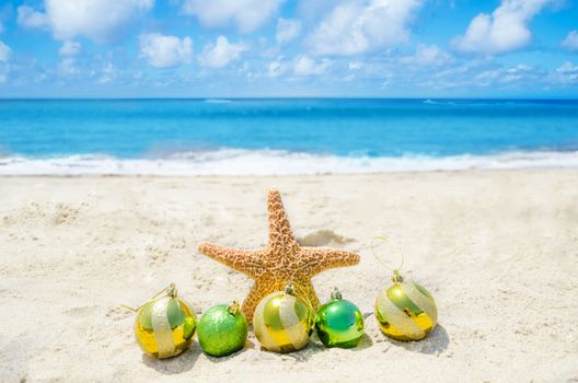 Starfish with Christmas balsl on sandy tropical beach in sunny day- holiday concept