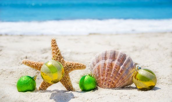 Starfish and seashell with Christmas balls on sandy beach in sunny day- holiday concept