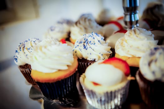 Selective focus on middle cupcake. Shallow depth of field. Various cupcakes on a tray, ready to be served.