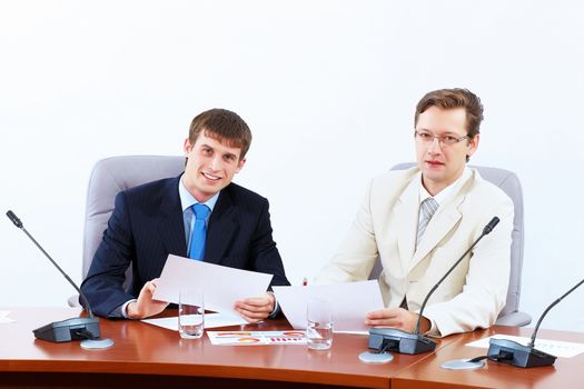 Image of two businessmen sitting at table at conference