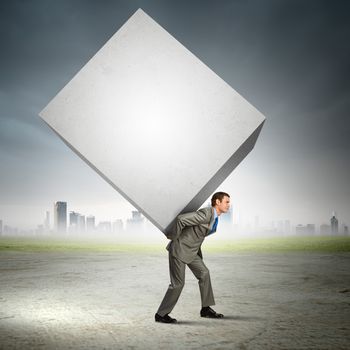 Image of businessman carrying big white cube on his back