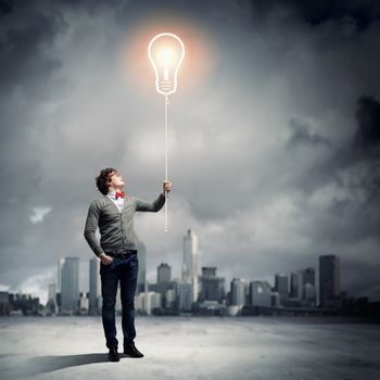 Young man holding a light at his hands against polluted and ruined landscape