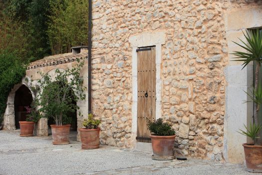 Beautiful exterior wall of an old stone building with potted plants standing alongside doors and arches