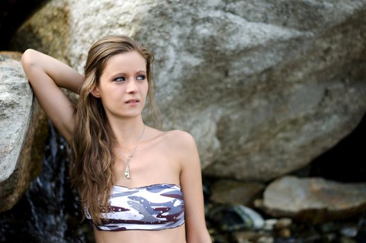 Pretty brunette girl in bikini against rocks