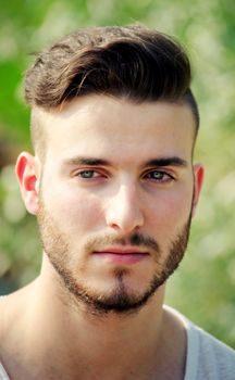 Headshot of handsome young man outdoors, serious expression