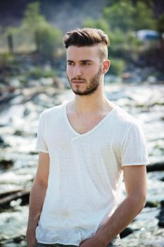 Portrait of handsome young man in white t-shirt outdoors, looking to a side