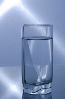 glass of water on reflective surface with blue lights in the background