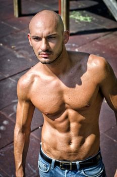 Bald young man shirtless outdoors standing wearing jeans