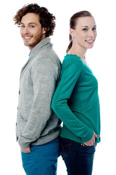 Trendy young smiling couple posing back to back