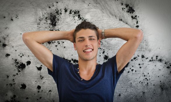 Handsome and confident young man smiling with arms up, spotted wall behind him