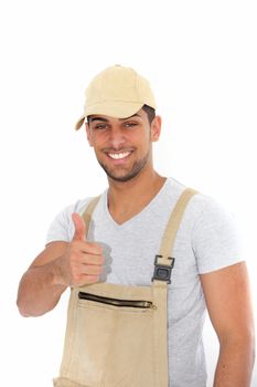Confident workman with a pleased smile giving a thumbs up of success and approval isolated on white