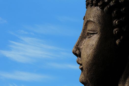 a buddha against a blue sky with clouds for meditation and enlightenment