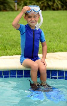 cute child sitting on edge of swimming pool outdoors in summer