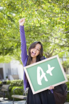Excited Mixed Race Female Student Holding a Chalkboard With A+ Written on it.
