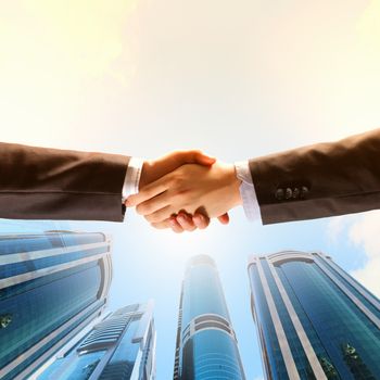 Close up image of hand shake against skyscrapers