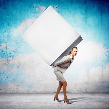 Image of businesswoman carrying big white cube on her back. Place for text