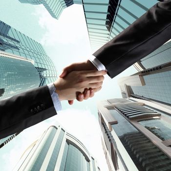 Close up image of hand shake against skyscrapers