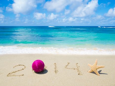 Number 2014 with christmas ball and starfish on the sandy beach