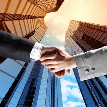 Close up image of hand shake against skyscrapers