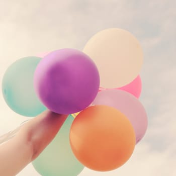 Hand holding multicolored balloons with retro filter effect