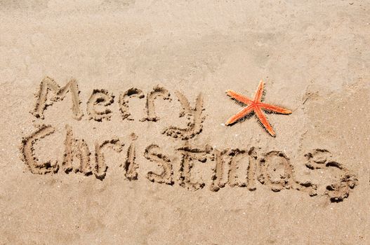 Merry Christmas written in the sand with star