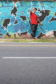 A greeting young Rapper greeting in front of a Graffiti wall.