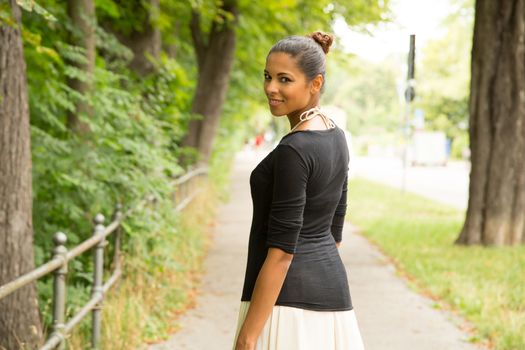 A young Girl walking in the park with her handbag.