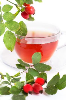 Cup of rose hip tea and berries over white