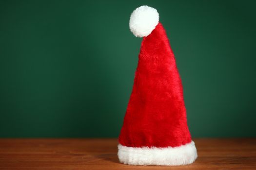 Santa Clause Red Hat With Copy Space on Green and Wood Background