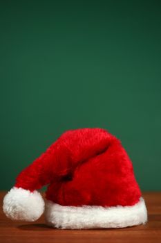 Santa Clause Red Hat With Copy Space on Green and Wood Background