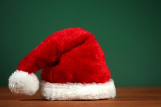 Santa Clause Red Hat With Copy Space on Green and Wood Background