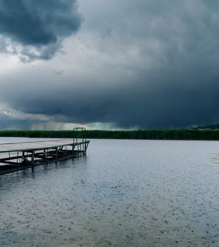 drops of rain on river under dark clouds