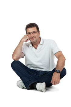 attractive healthy adult man sitting on floor with glasses and jeans t-shirt casual lifestyle isolated