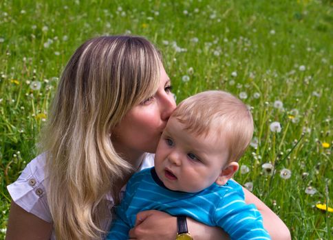 young mother with her son on the green grass
